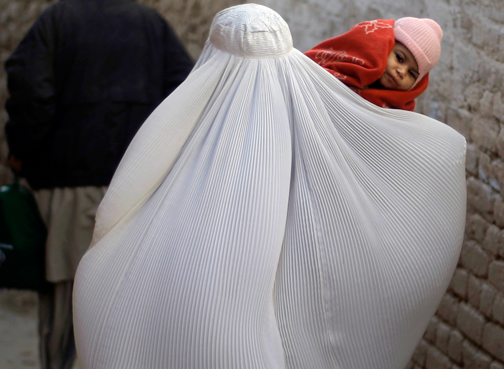 Мусульманская женщина несёт на руках дочку.