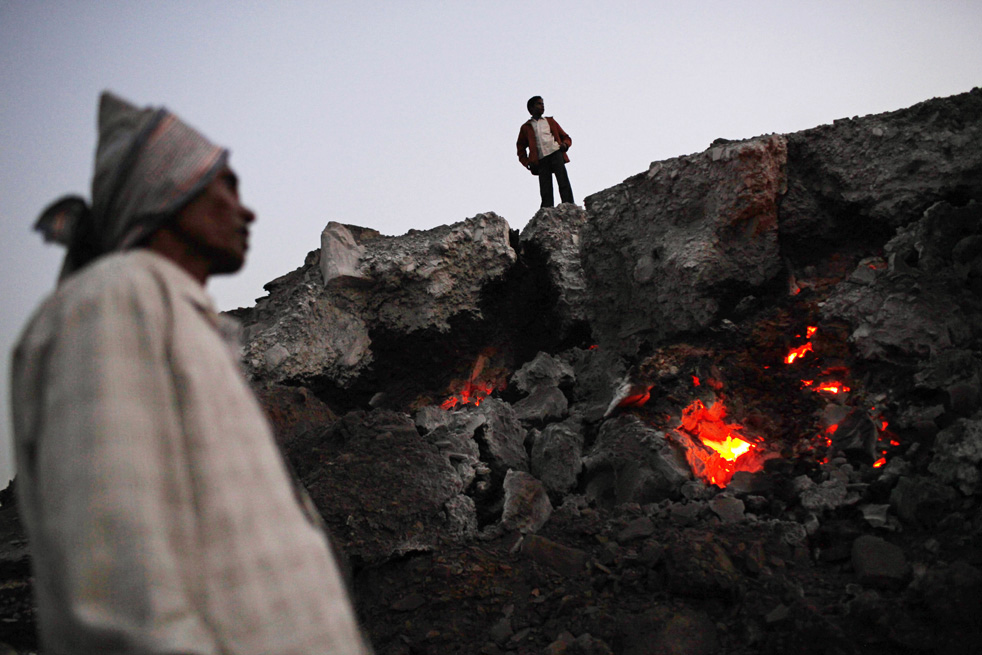 Люди стоят рядом с горящим углем.