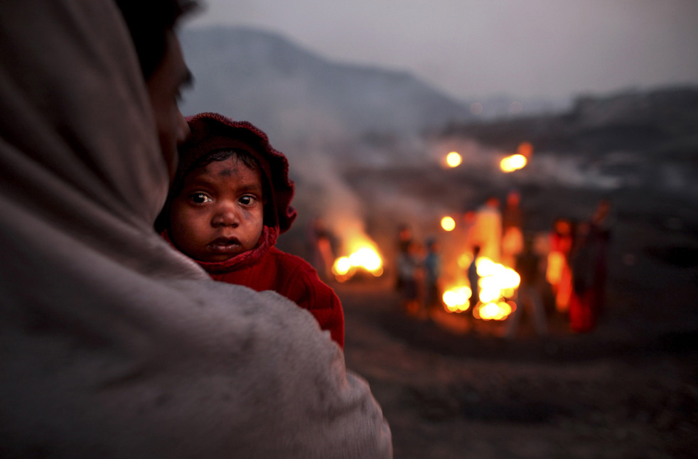Мужчина с ребёнком стоит около горящего угля.