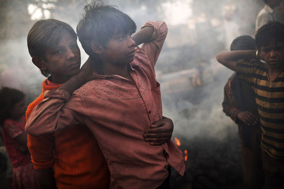 Молодые люди стоят около горящего угля.