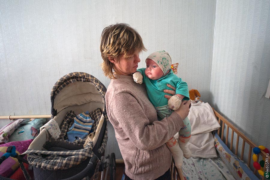 Обитательниа центра "Колыбель" держит на руках ребёнка.