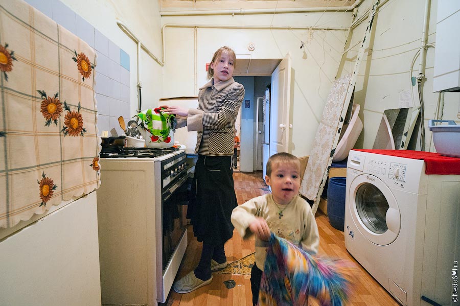 Девочка стоит у плиты, мальчик бежит с полотенцем на кухне центра "Колыбель".