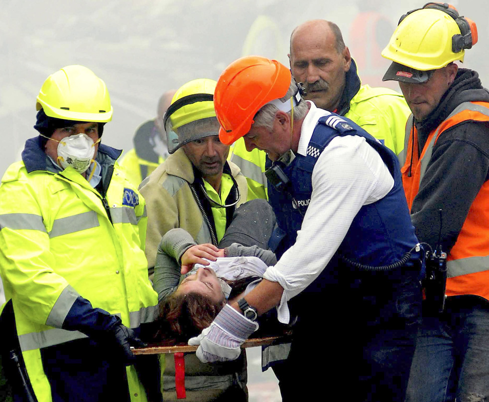 Спасатели несут на носилках женщину.