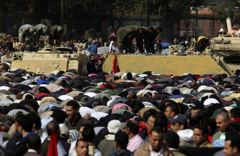 Участники антиправительственных выступлений и военные совершают традиционную мусульманскую пятничную молитву во время продолжающейся демонстрации на площади Тахрир в Каире. Египет, 11 февраля 2011 года. (AP / Khalil Hamra)