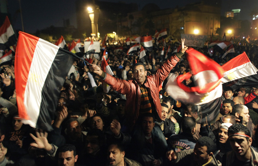 Египтянин сидит на плечах у товарища и машет флагами.