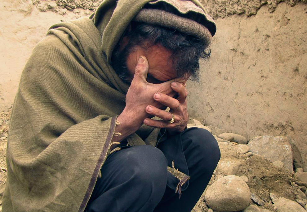 Афганский мужчина сидит и плачет.