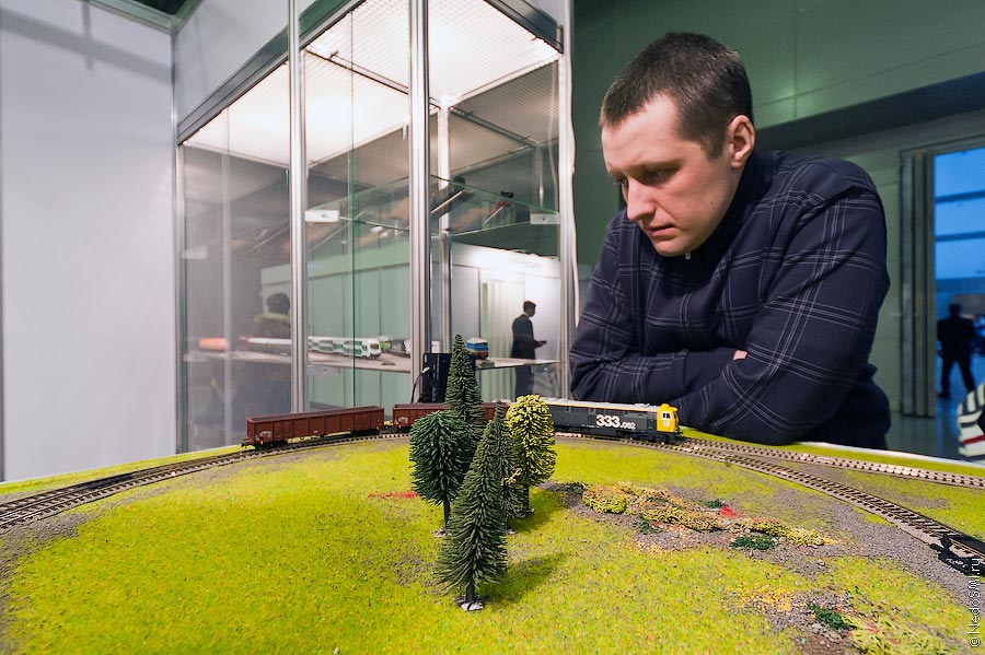 Человек смотрит на игрушечный поезд.