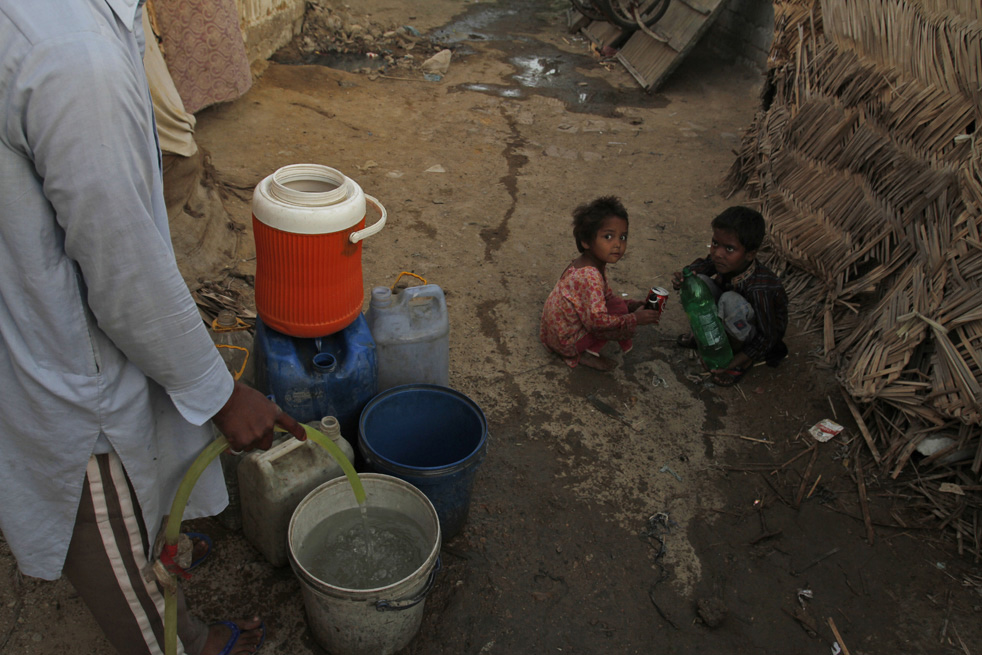 Человек набирает воду, а рядом играют дети.