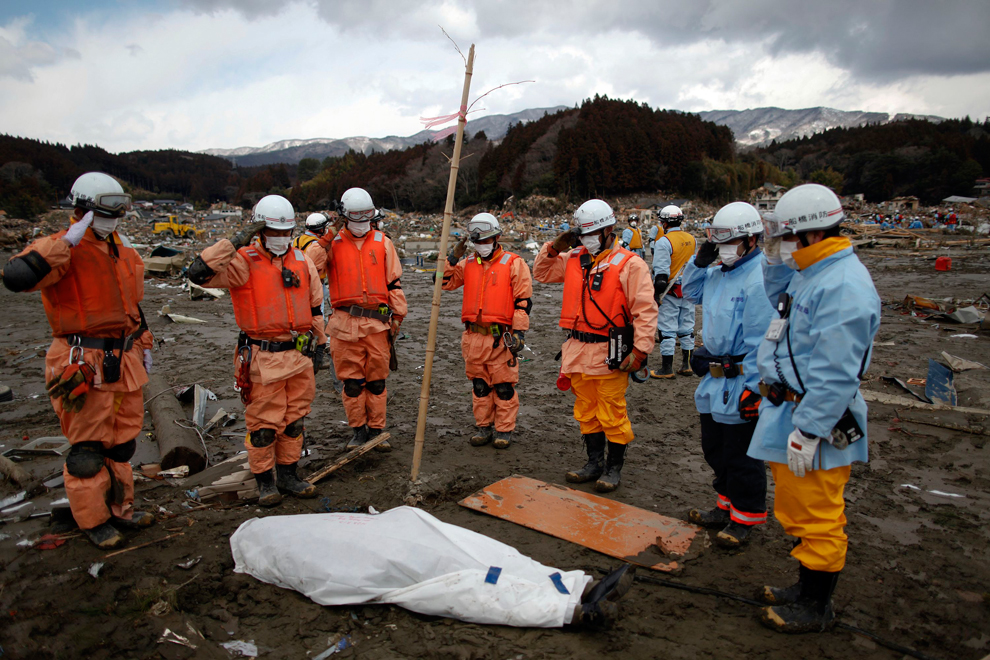 Спасатели стоят около найденного тела.