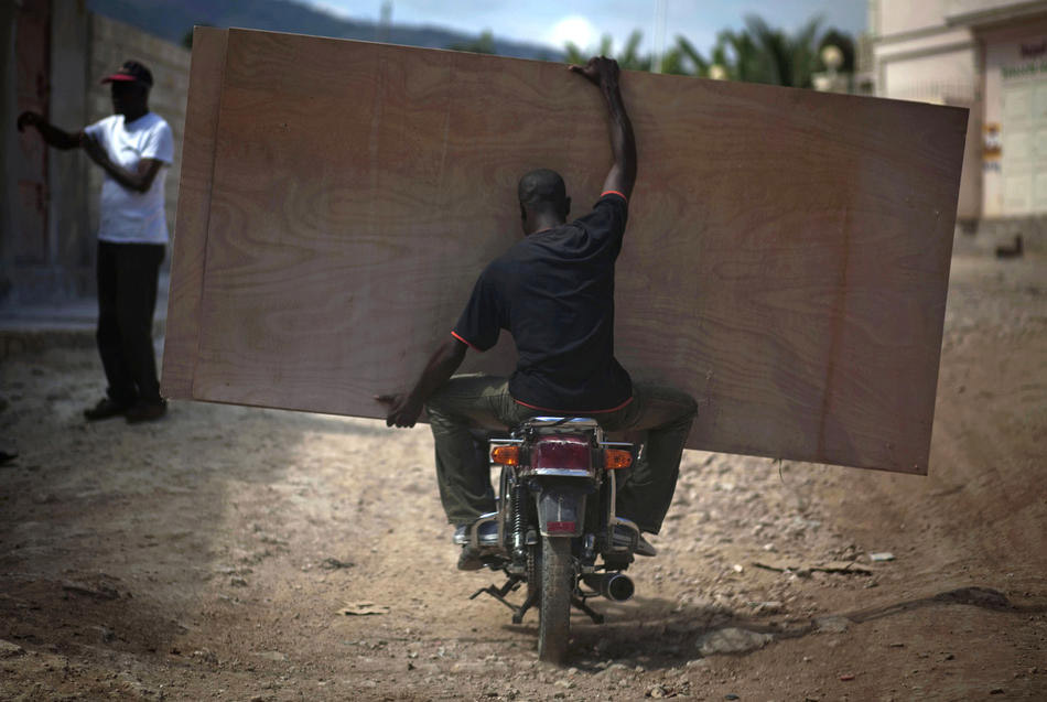 Мужчина перевозит на мотоцикле листы фанеры