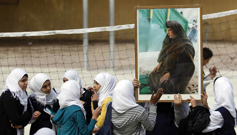 Школьницы держат портрет ливийского лидера Муаммара Каддафи 