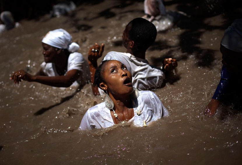 Люди купаются в священном бассейне во время церемонии Вуду, которая проходила в это воскресение в Сувеннанс, на Гаити.
