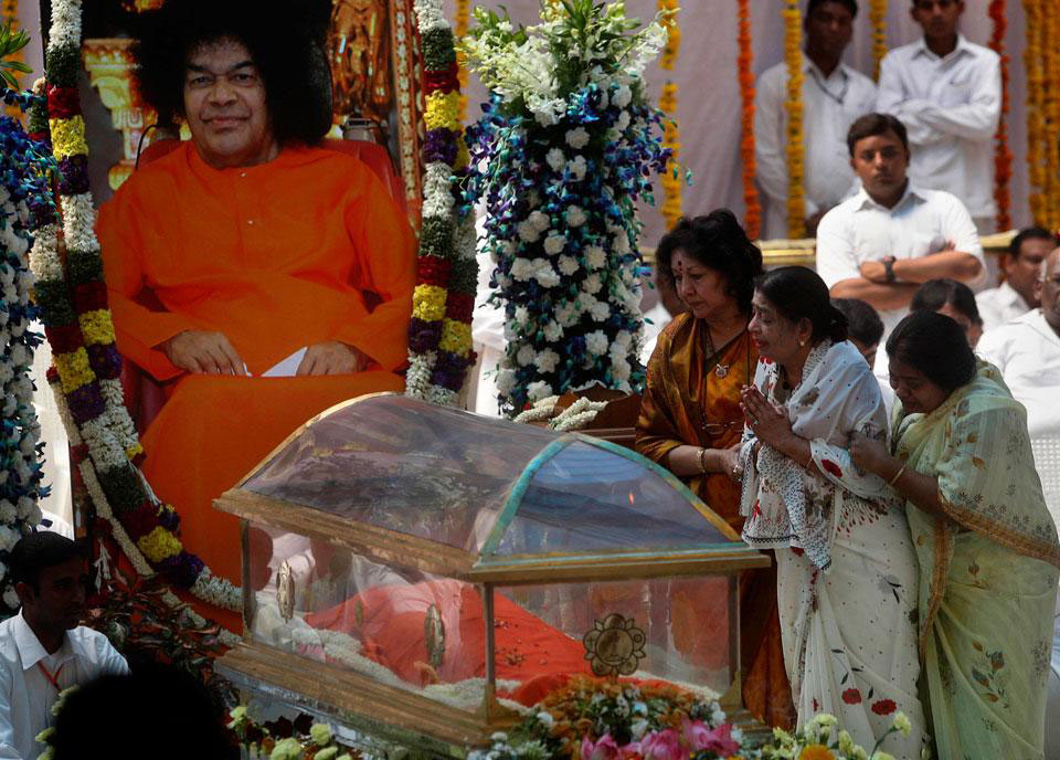 Последователи индийского религиозного лидера Сатья Саи Бабы скорбят рядом с его телом.