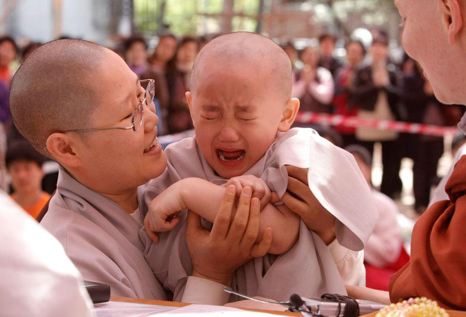 Ребенок по имени Йо Джин плачет, потому что согласно традиционному буддистскому обряду монах положил раскаленный ладан на его руку.