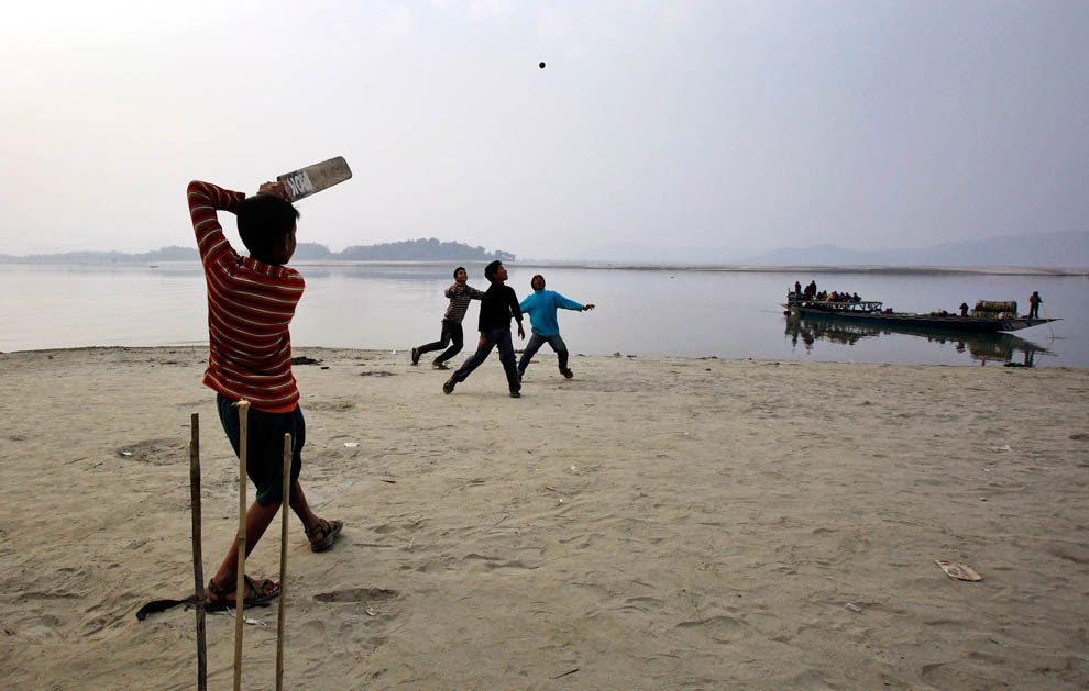 Дети играют в крикет на берегу реки