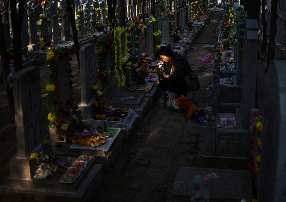Женщина кладёт цветы на могилу