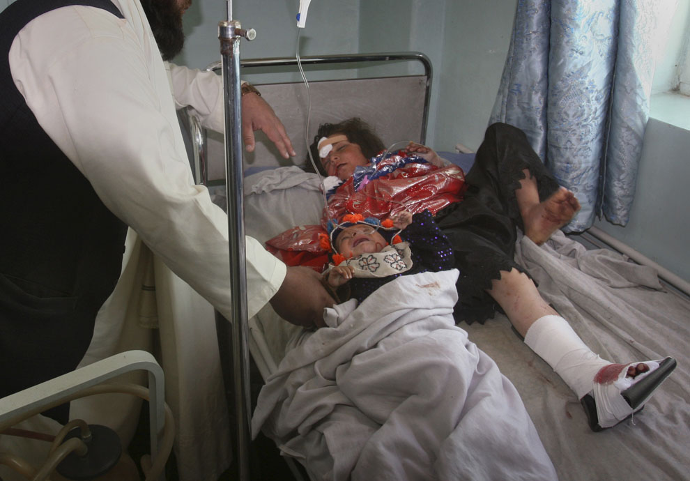 Раненый ребенок лежит рядом с раненой женщиной