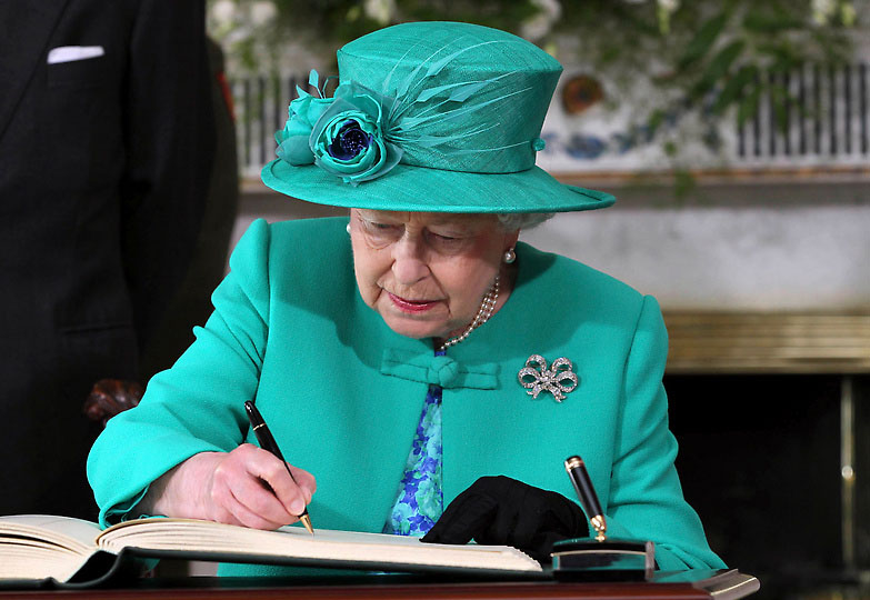 Королева делает запись в книге посещения