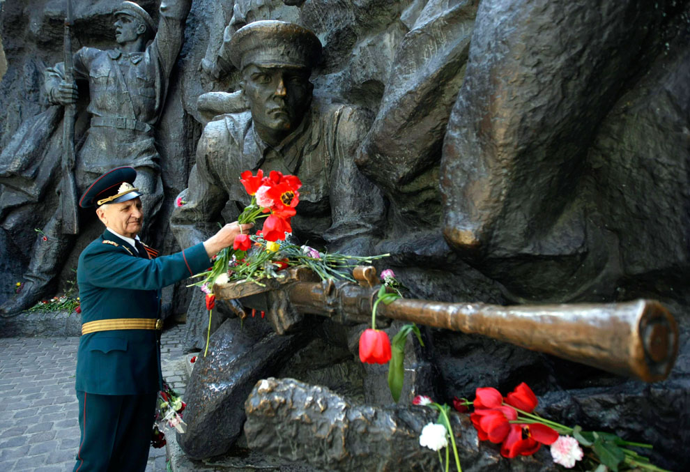Ветеран войны возлагает цветы к памятному мемориалу