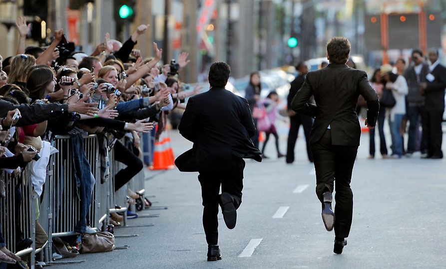 Актер Брэдли Купер (справа) бежит по Голливудскому бульвару