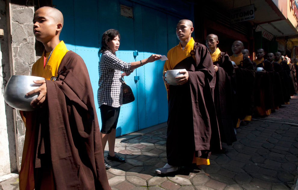 Женщина дает пожертвование буддистским монахам