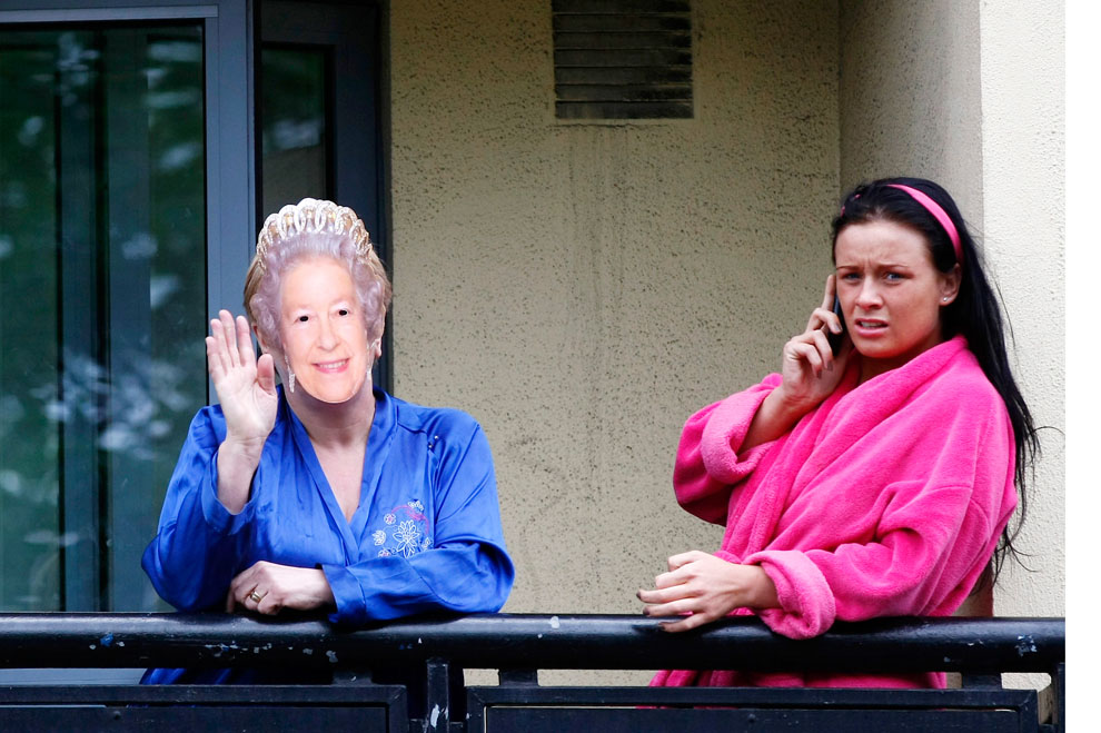 Женщина надела маску Елизаветы II и машет с балкона