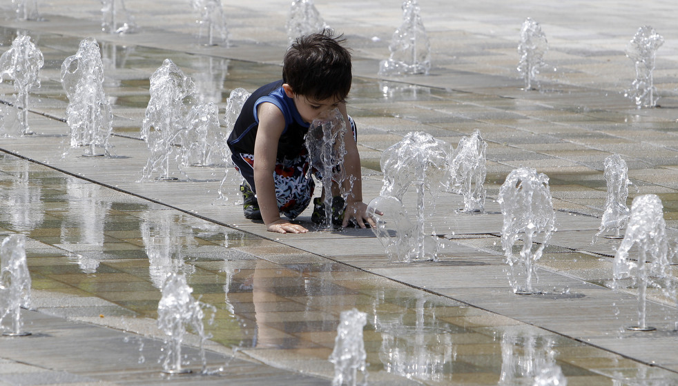Мальчик играет в фонтане 