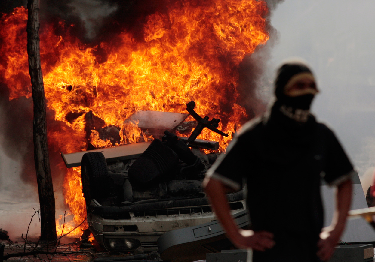 Демонстрант и горящий автомобиль