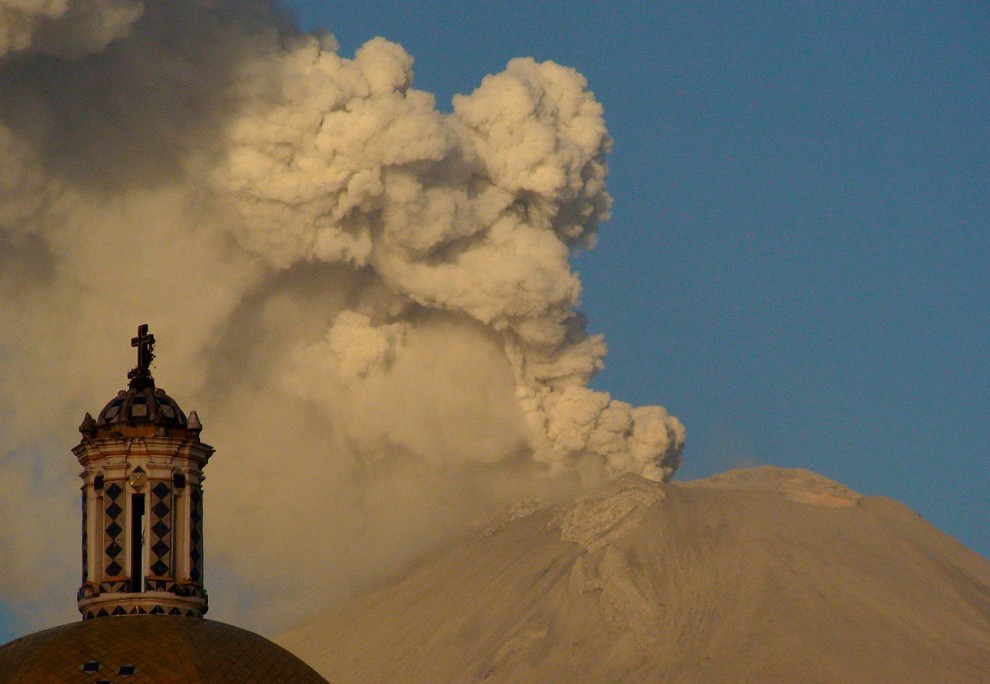 Облако дыма поднимается из кратера вулкана Попокатепетль. Вид из города Чолула в мексиканском штате Пуэбла, 24 мая 2012 года. У подножия вулкана находится Церковь Богоматери (на переднем плане). (AP Photo/Chema Alvarez)