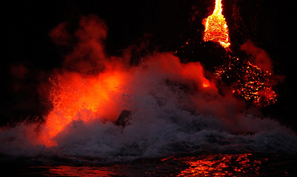 Пар поднимается от горячей лавы, которая стекает в море, в национальном парке Гавайские вулканы в Калапане, Гавайи, 27 ноября 2012 года. 