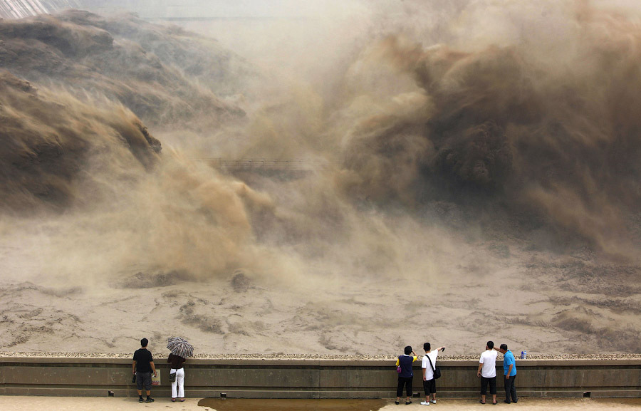 Туристы смотрят на сброс воды на плотине Xiaolangdi в Jiyuan, Китай, 6 июля 2012 г.
