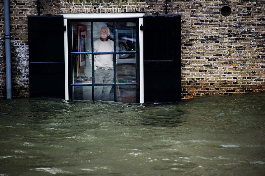 Житель города Дордрехт смотрит в окно своего дома на наводнение, Голландия, 5 января 2012 г.