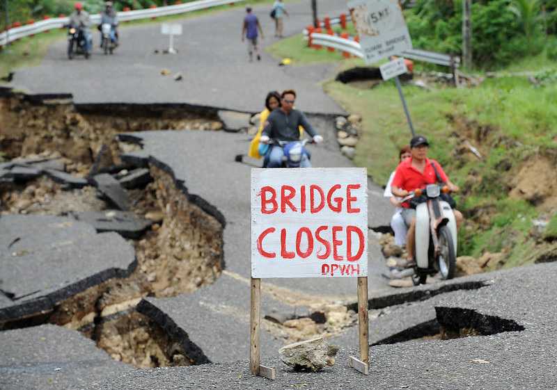 Люди едут по разрушенной землетрясением дороге в городе Guihulngan, Филиппины, 9 февраля 2012 года.