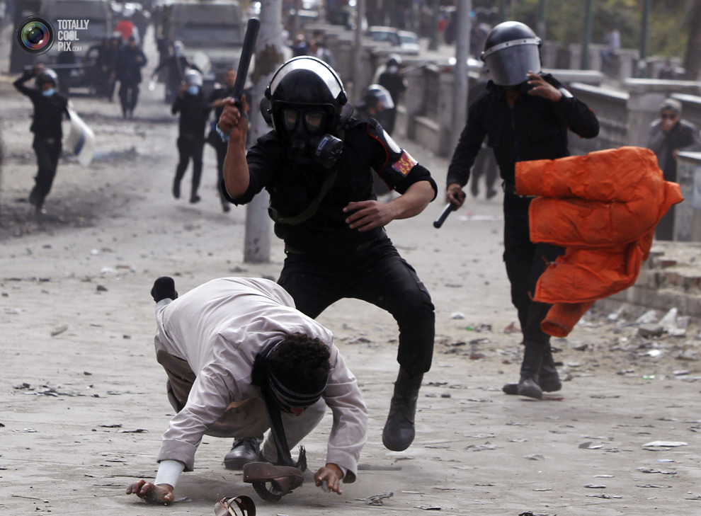 Полицейский бьёт демонстранта, выступающего против президента Мухаммеда Мурси, во время столкновений в Каире, Египет. 