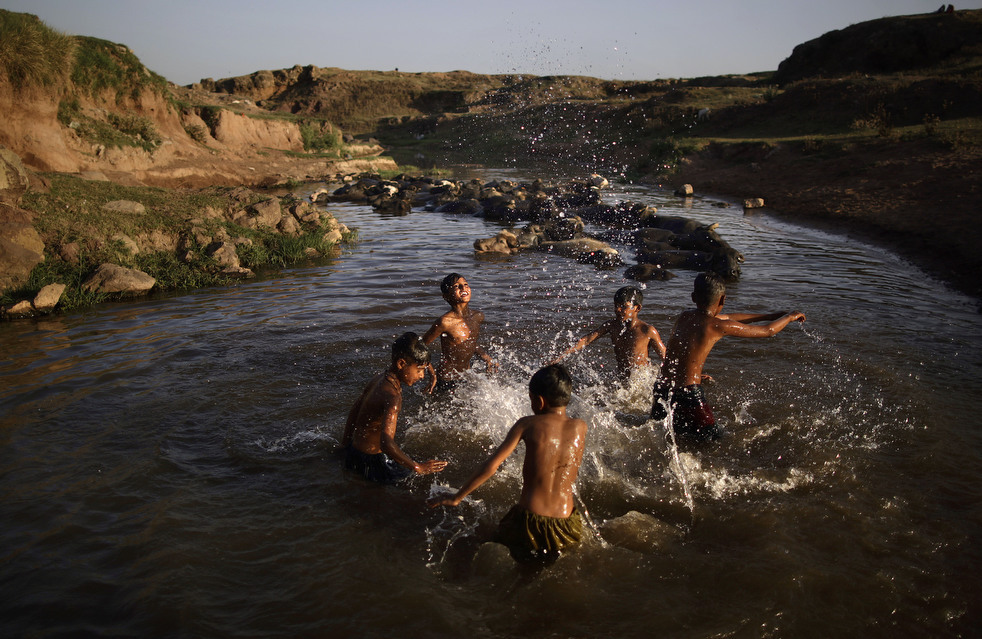 Мальчики купаются рядом с буйволами в грязной реке после работы на оптовом рынке на окраине Исламабада, Пакистан, 16 мая 2013 года. (AP / Muhammed Muheisen)