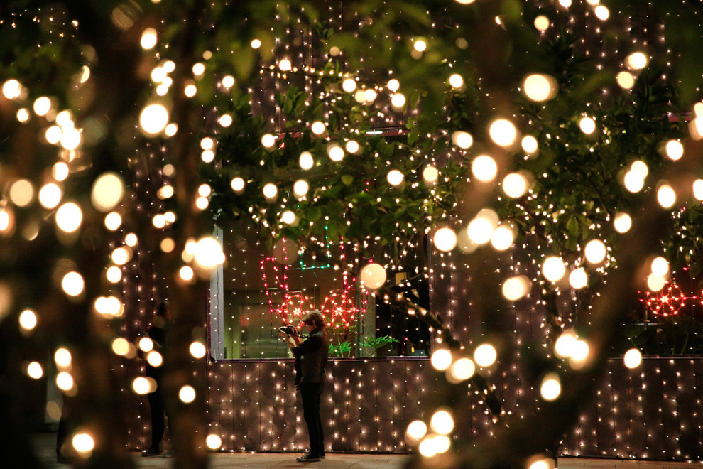 Женщина фотографирует рождественские декорации на площади Першинг в Лос-Анджелесе, 6 декабря. (Jae C. Hong/Associated Press) 