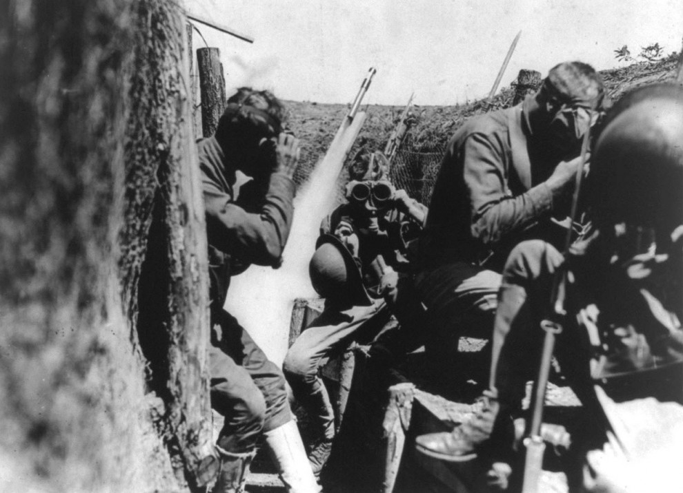 Американские солдаты надевают противогазы в окопе. За ними на заднем плане взлетает сигнальная ракета. (Library of Congress)