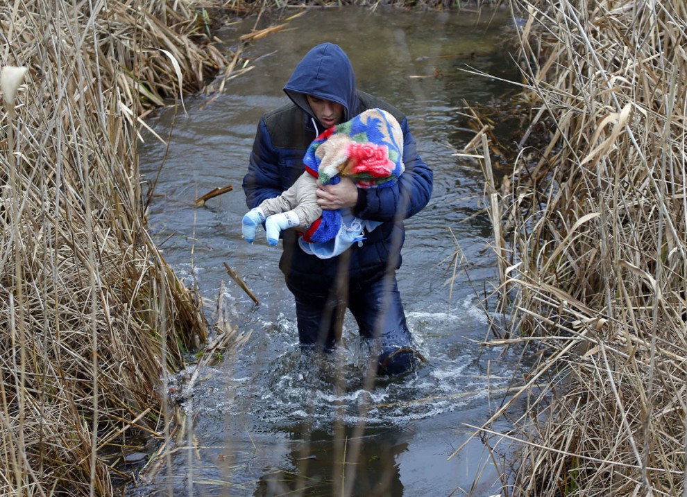Косовар с ребёнком нелегально пересекает сербско-венгерскую границу возле деревни Ашотхалом, Венгрия, 6 февраля. 