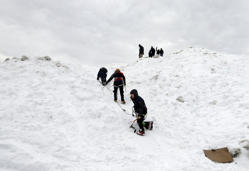 Студенты Массачусетского технологического института в шутку взбираются на огромную кучу снега при помощи альпинистского снаряжения на территории своего кампуса в Кембридже, штат Массачусетс, США, 18 февраля 2015 года.