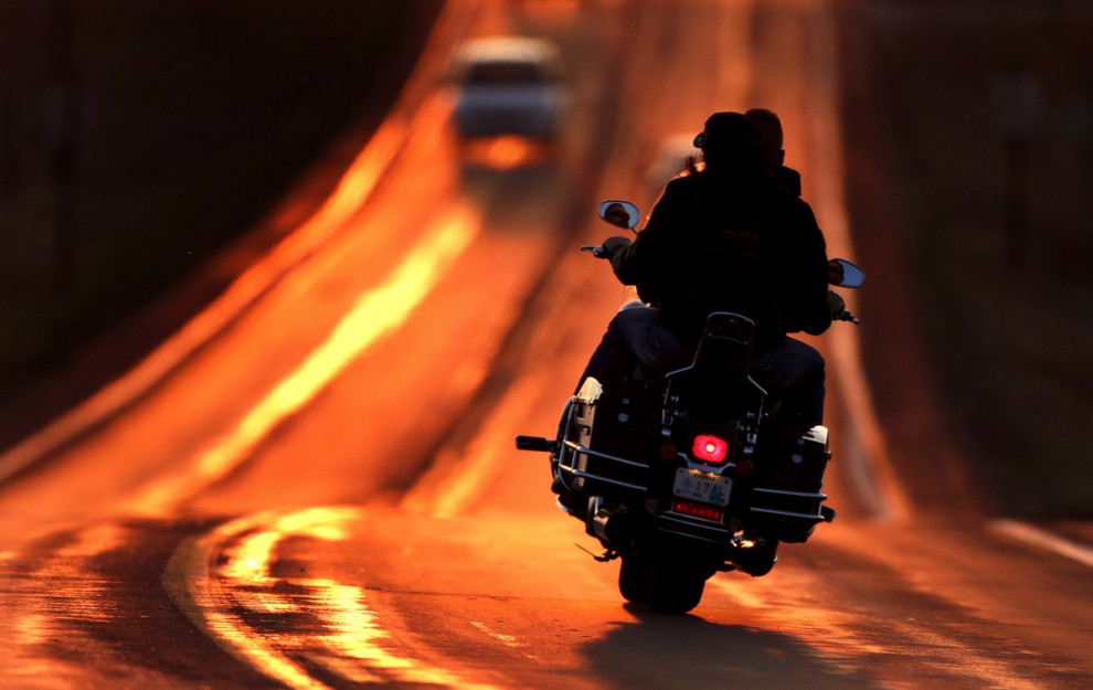 Мотоциклист едет по трассе в  лучах заката в Лоренсе, штат Канзас, США, 21 марта 2015 года.