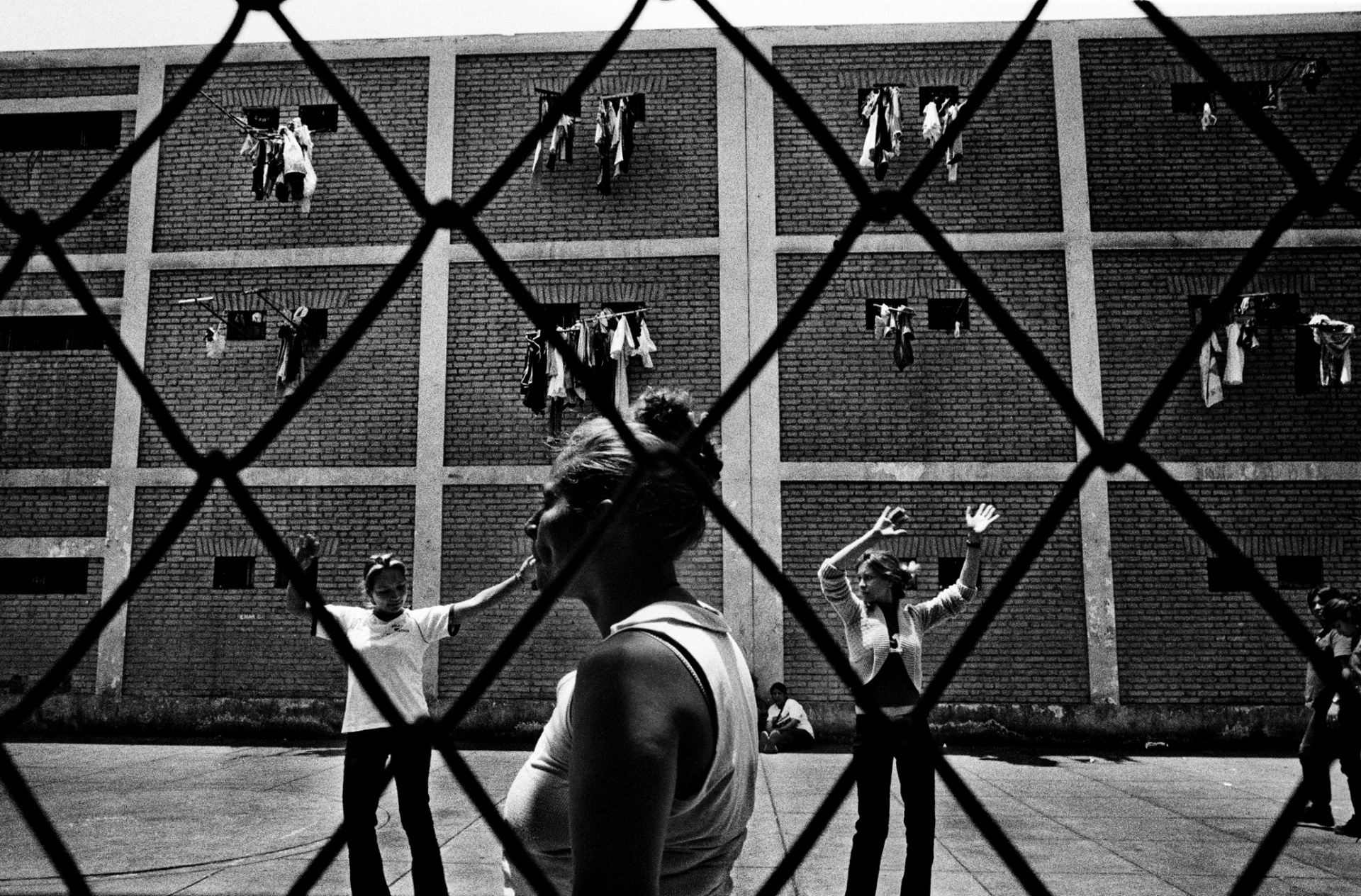 Чоррильос, женская тюрьма, Лима, Перу, 2007 Во время своего путешествия, Валерио Биспури видел мужчин, которые только что бросались друг на друга с ножами, и позже играли в футбол друг с другом, и женщин-заключенных, танцующих танго. На данной фотографии мы видим, как две молодые женщины танцуют, возможно разучивая какие-то движения из степа. 
